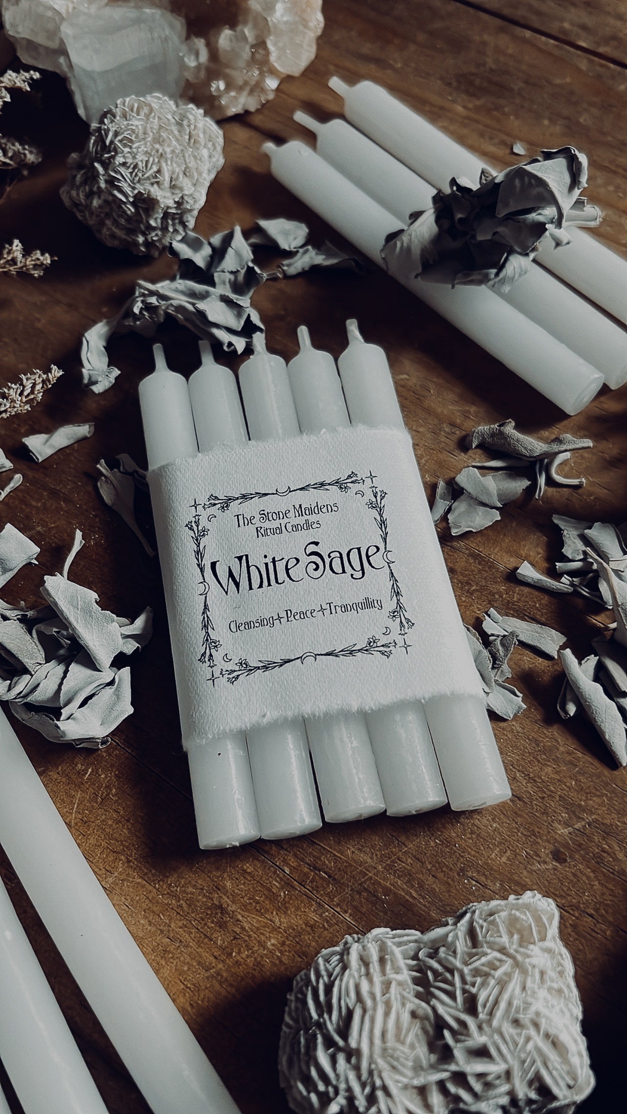 White Sage Ritual Candles arranged on a dark wooden altar surrounded by sage. Sold at The Stone Maidens