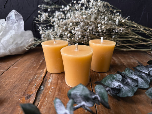 Hand-Dipped Canadian Beeswax Votive Candle, Natural Honey Scent. Three amber-colored candles on a wooden surface with decorative elements.