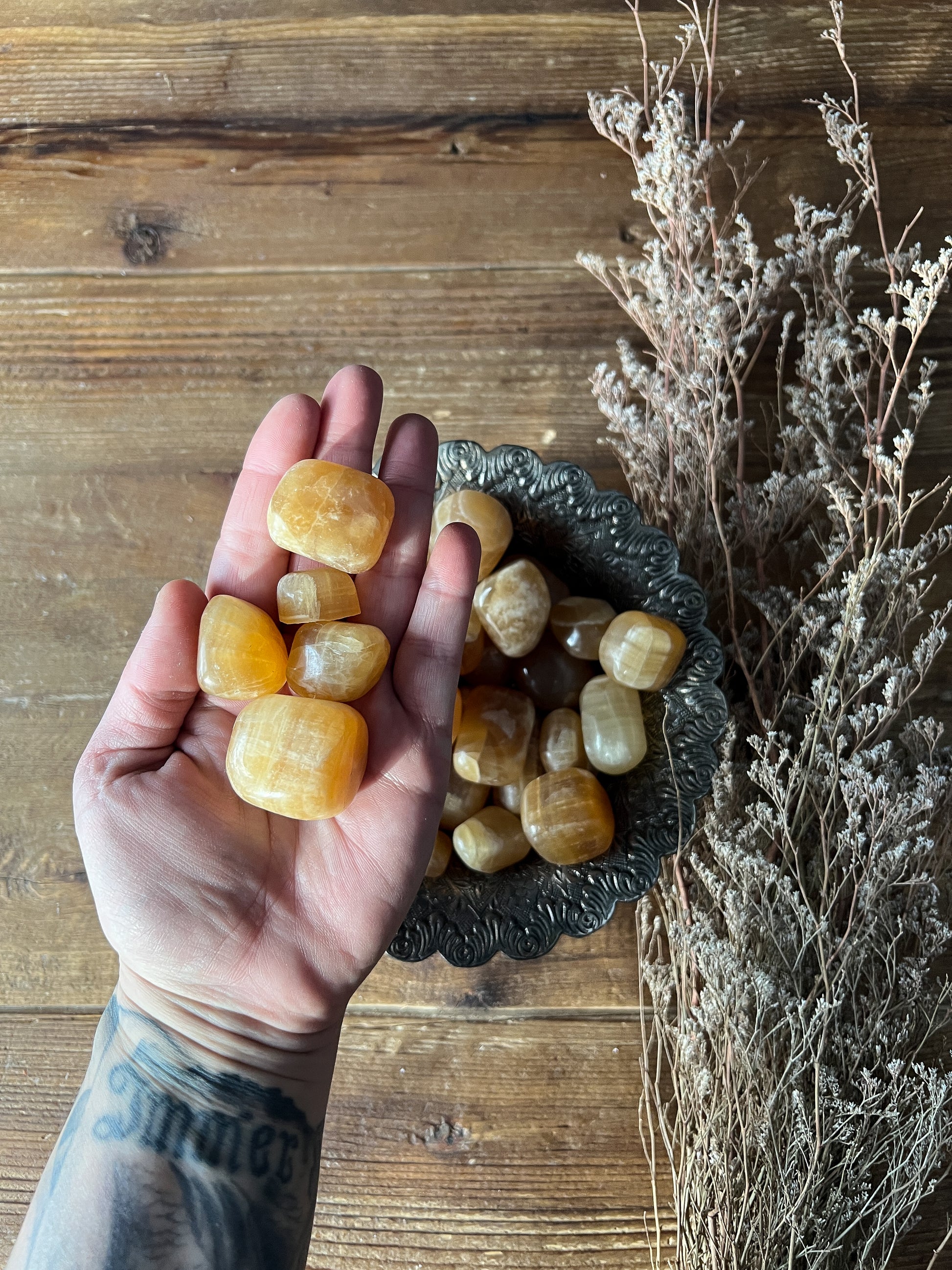 a few different sizes of the Honey Calcite Tumbled stones in The Stone Maidens hand.