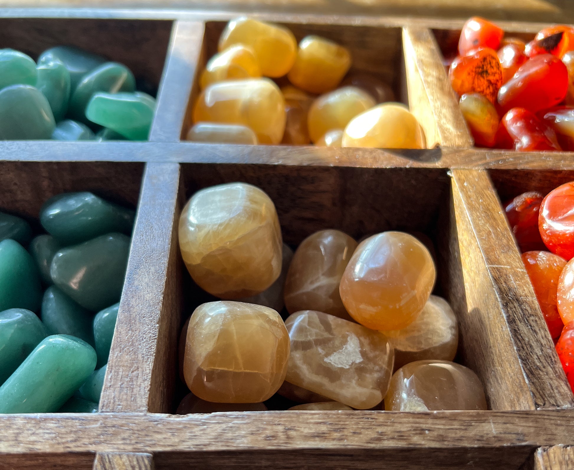 a close up shot of Honey Calcite Tumbled stones in a vintage wood apothecary drawer. The Stone Maidens sells a variety of Tumbled stones, pocket stones, palm stones.