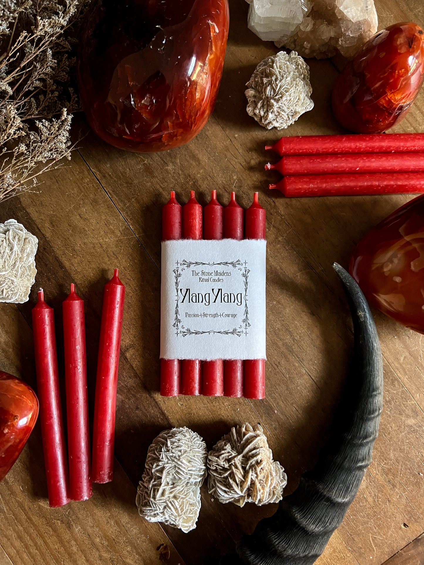 Ylang Ylang Red ritual candles arranged  on a dark wooden altar surrounded by crystals, sold at The Stone Maidens