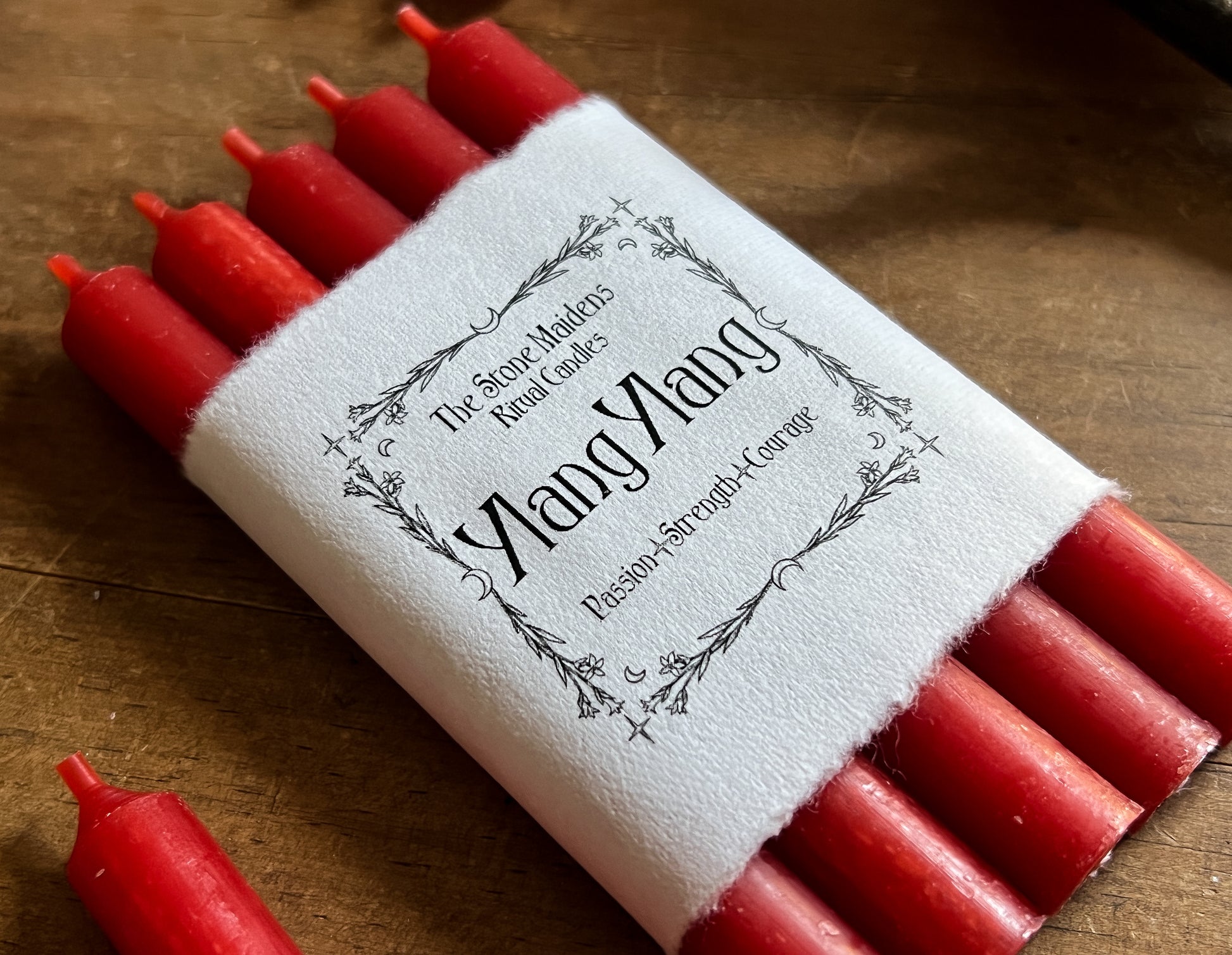 Ylang Ylang Red ritual candles arranged on a dark wooden altar, sold at The Stone Maidens