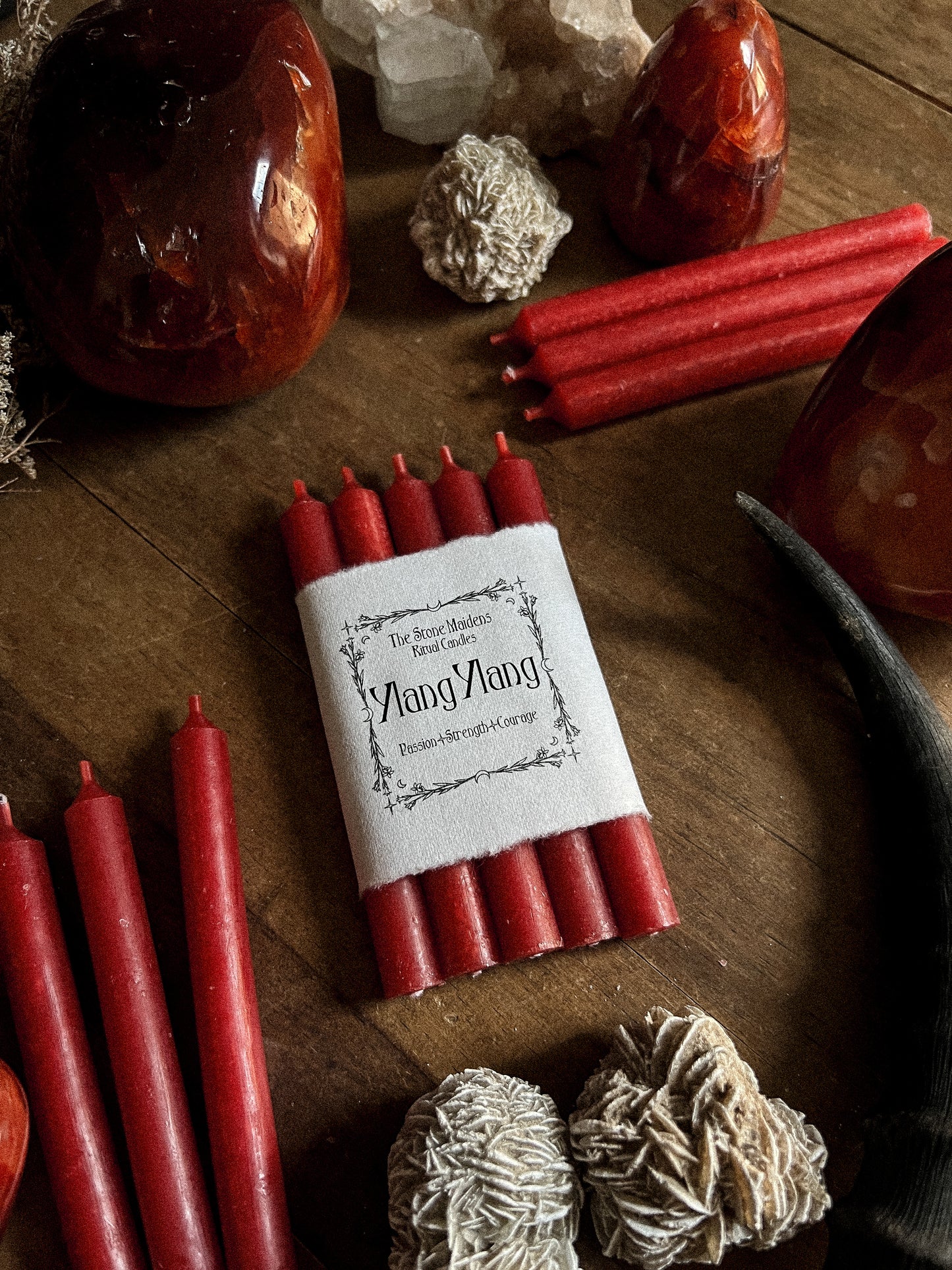 Ylang Ylang Red ritual candles arranged on a dark wooden altar surrounded by crystals, sold at The Stone Maidens
