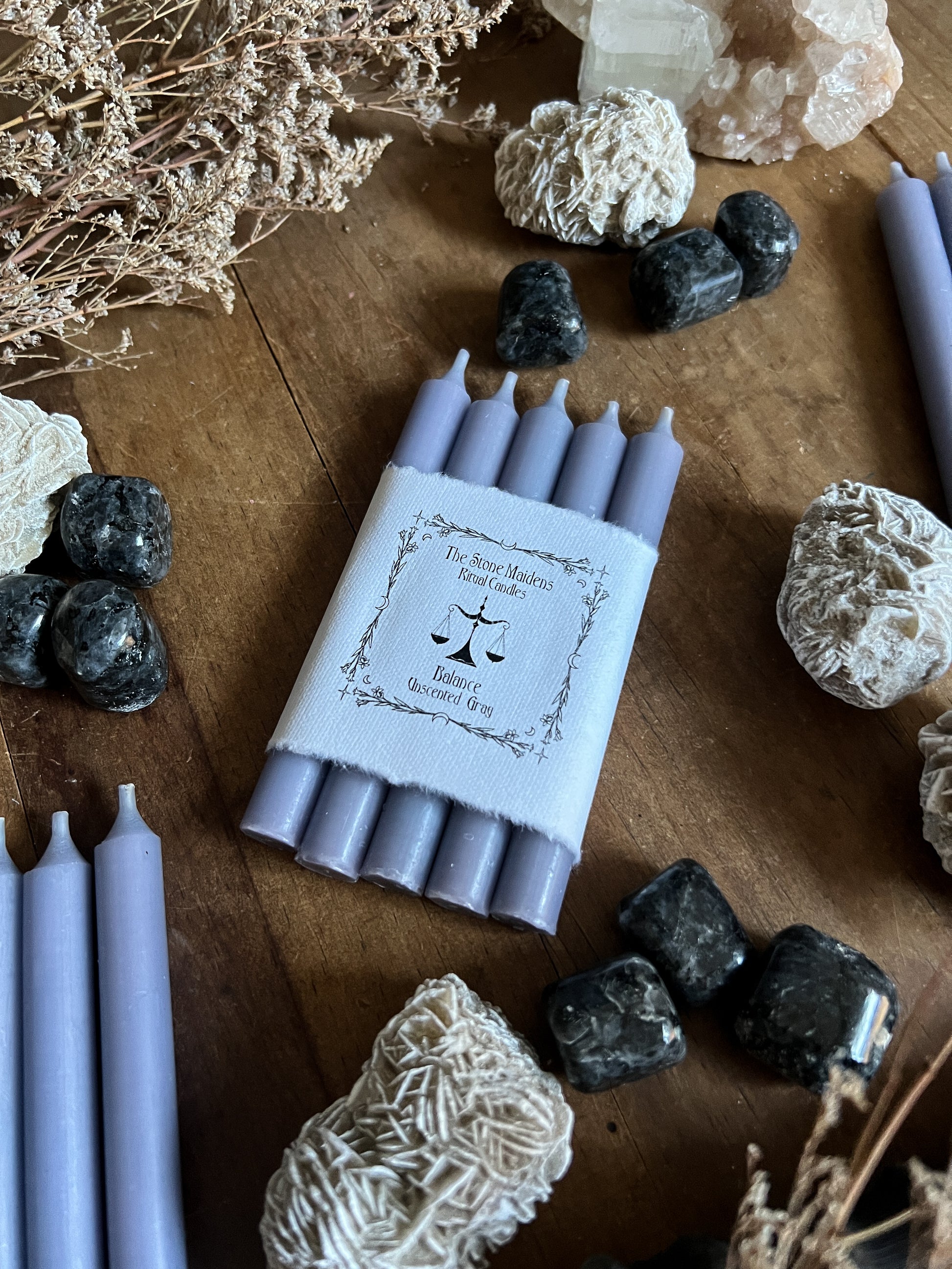 Gray Unscented ritual candles arranged on a dark wooden altar surrounded by crystals, sold at The Stone Maidens