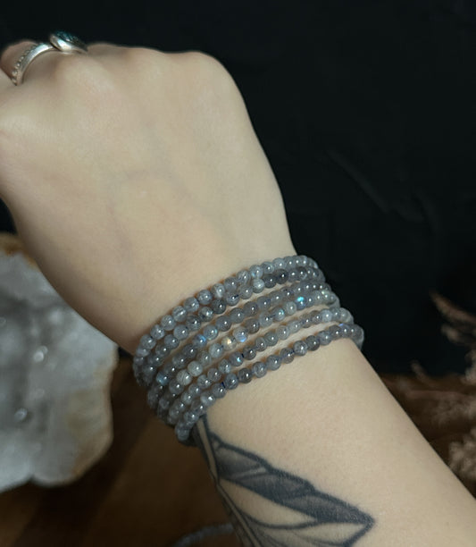 Close-up photograph of a 4mm Labradorite Bracelet, displaying its iridescent flashes of blue and green. 