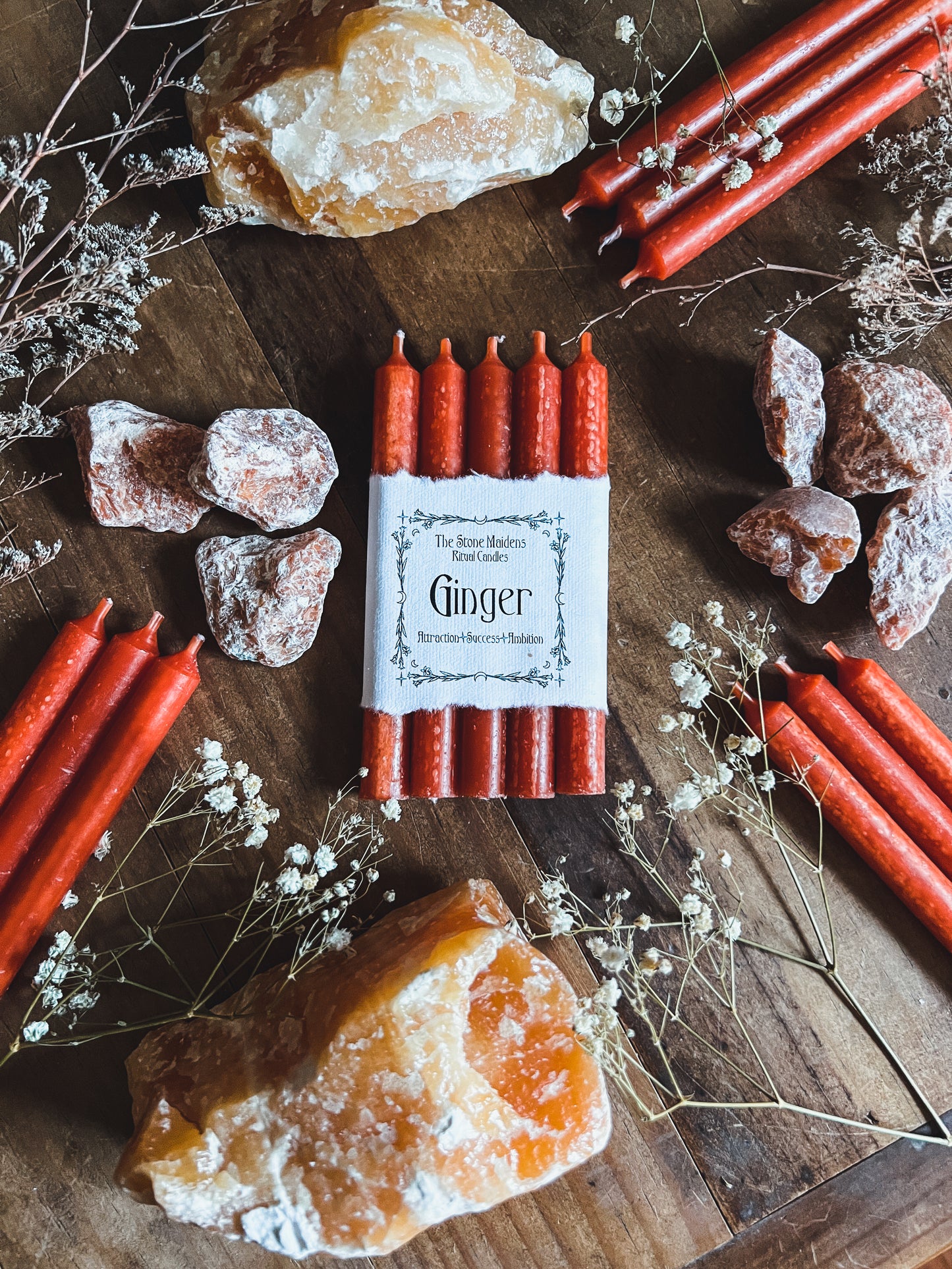 Ginger ritual candles arranged on a dark wooden altar surrounded by crystals, sold at The Stone Maidens