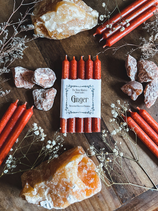 Ginger ritual candles arranged on a dark wooden altar surrounded by crystals, sold at The Stone Maidens