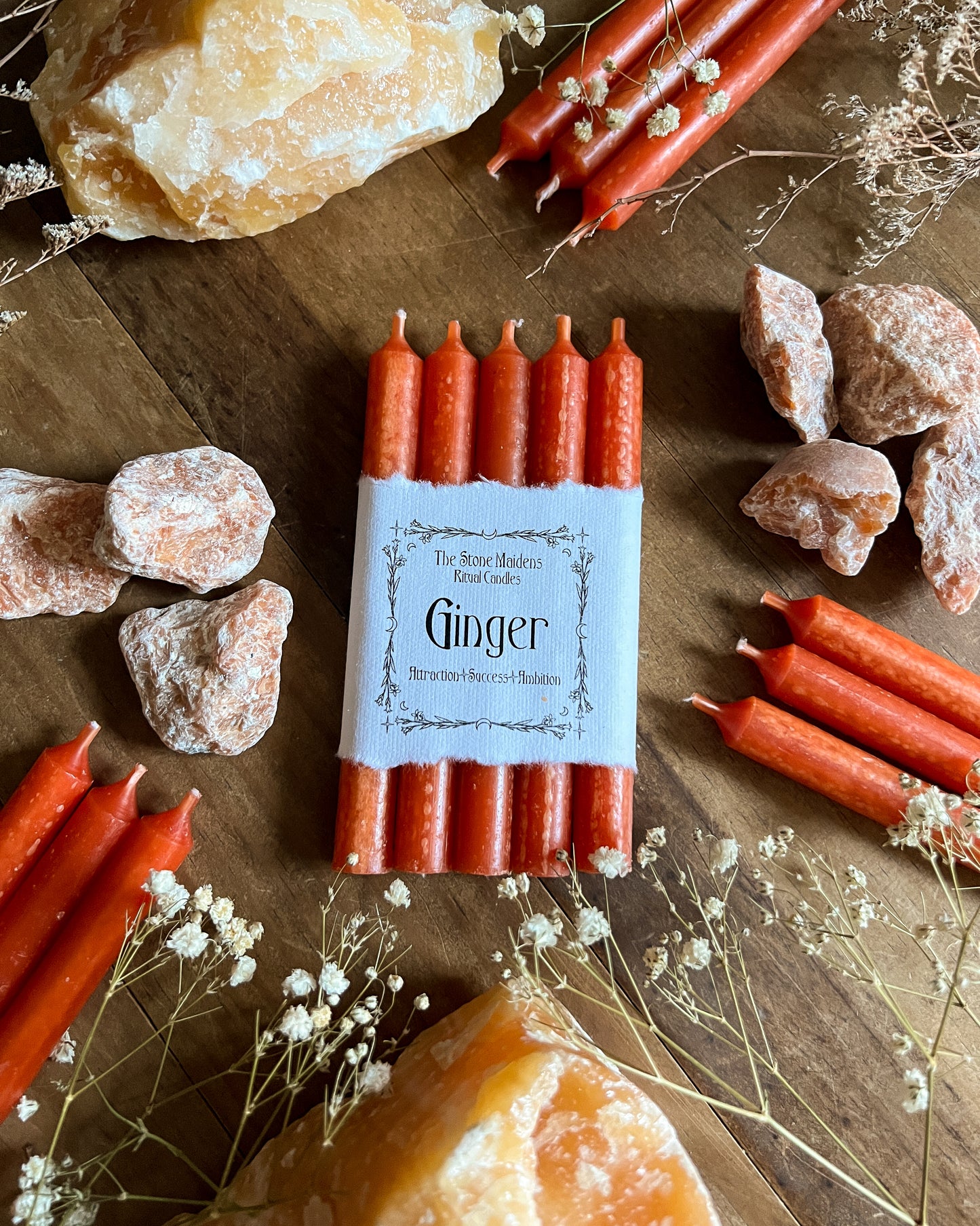 Orange Ginger chime candles arranged on a dark wooden altar surrounded by crystals, sold at The Stone Maidens