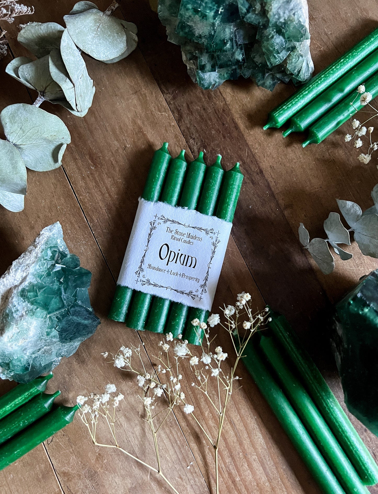 Opium Green Chime candles arranged on a dark wooden altar surrounded by crystals, sold at The Stone Maidens