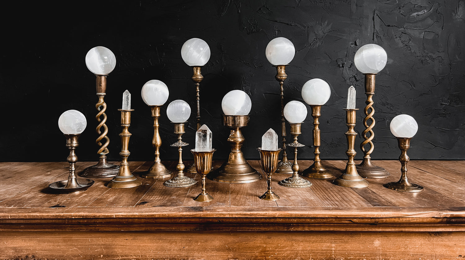 Brass stands and Selenite Spheres displayed on a wood altar. 