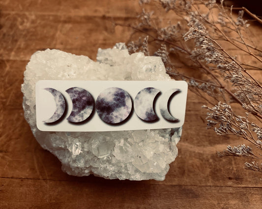 Purple Moon Phases sticker resting on an Quartz cluster.