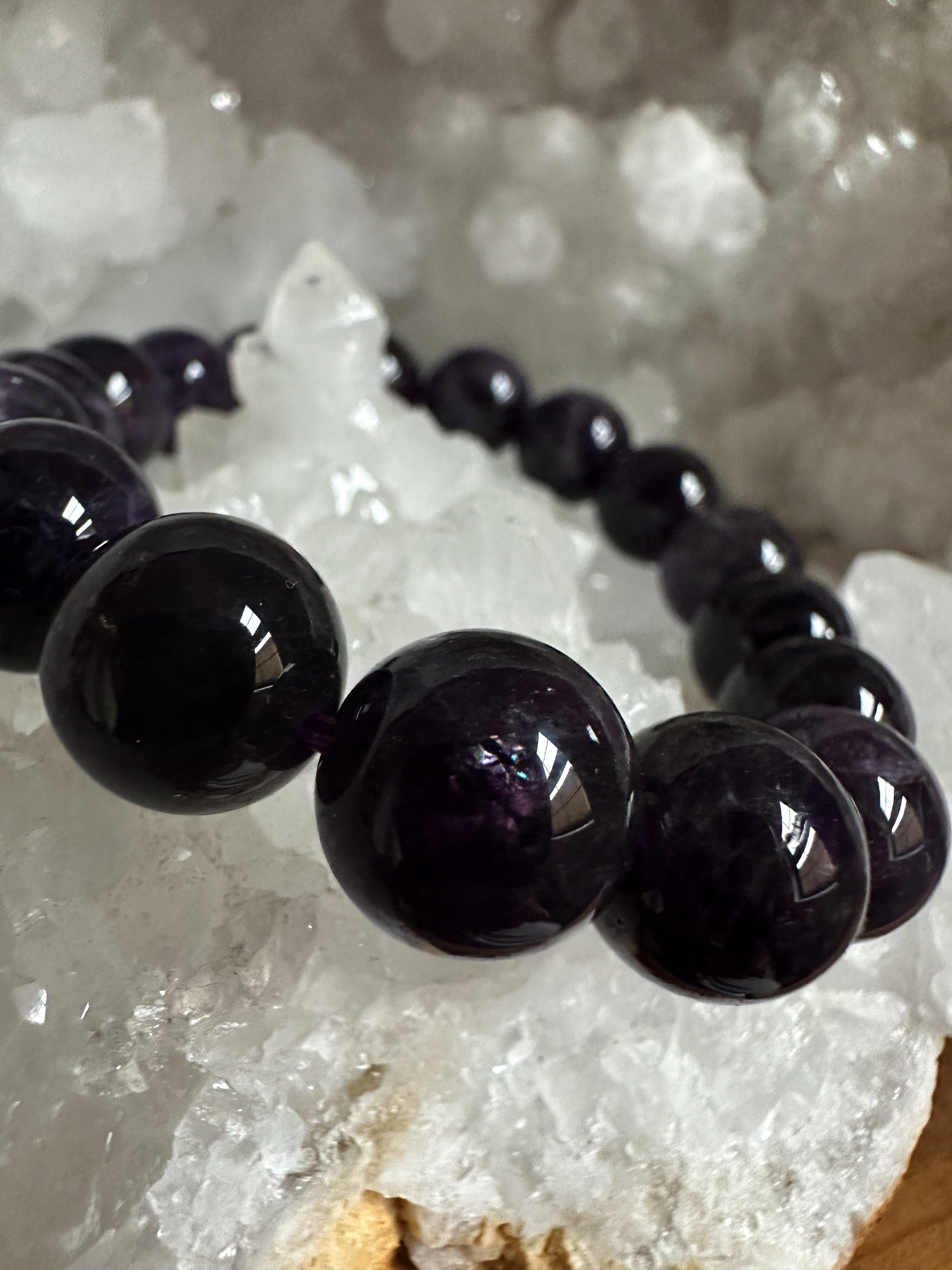 Close-up photograph of a 12mm Amethyst Crystal Bracelet, showcasing its, dark tones and shimmering inclusions