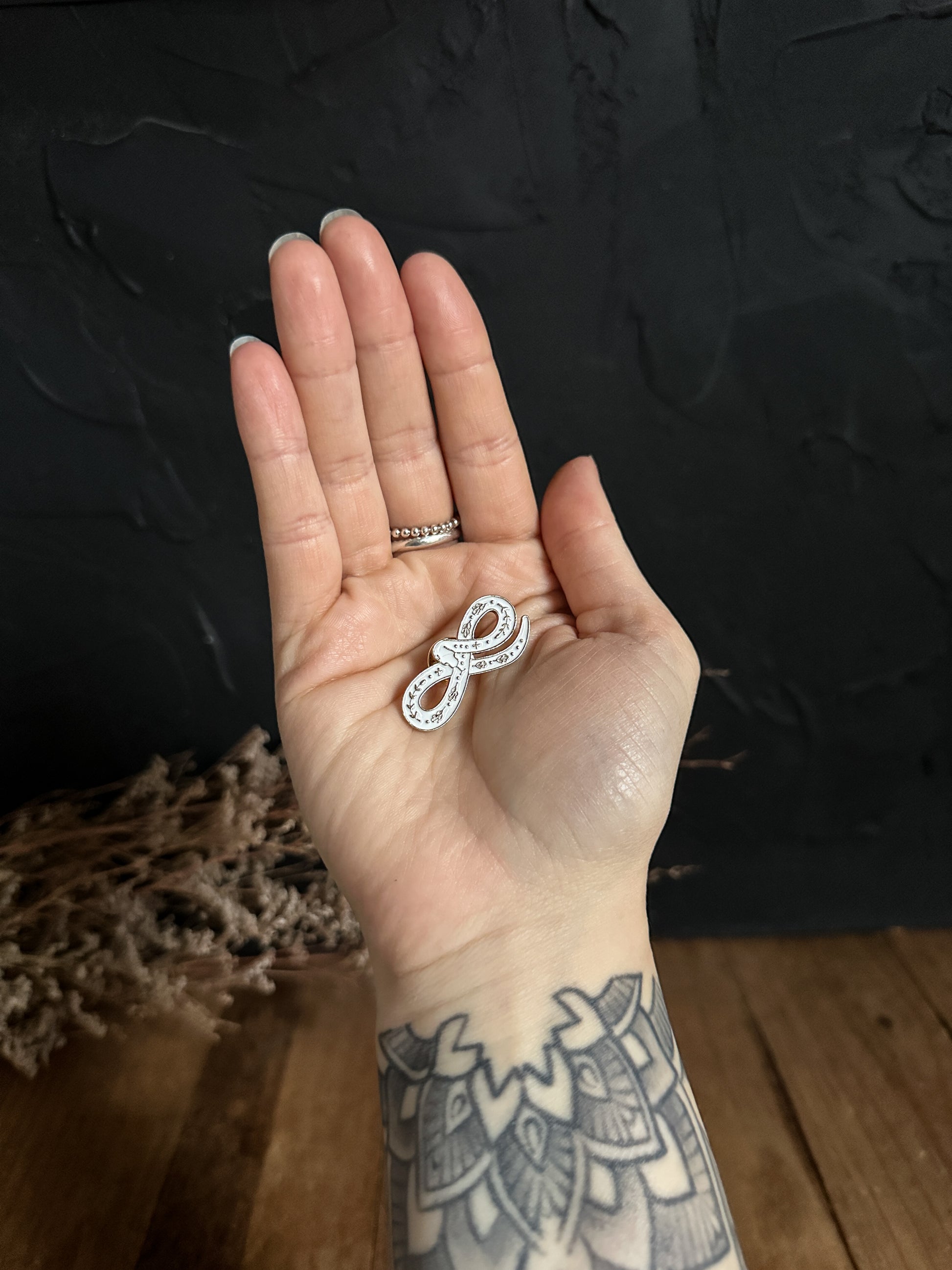 White Snake Enamel Pin in the hand of The Stone Maidens 