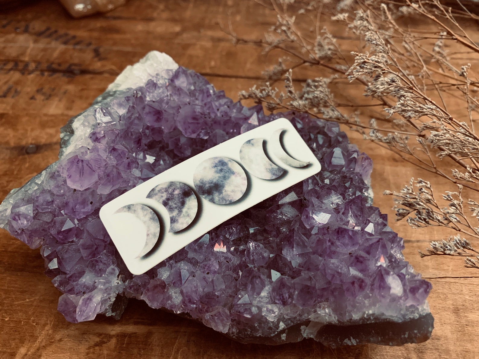 Purple Moon Phases sticker resting on an Amethyst cluster.